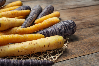 Photo of Many different raw carrots on wooden table, closeup