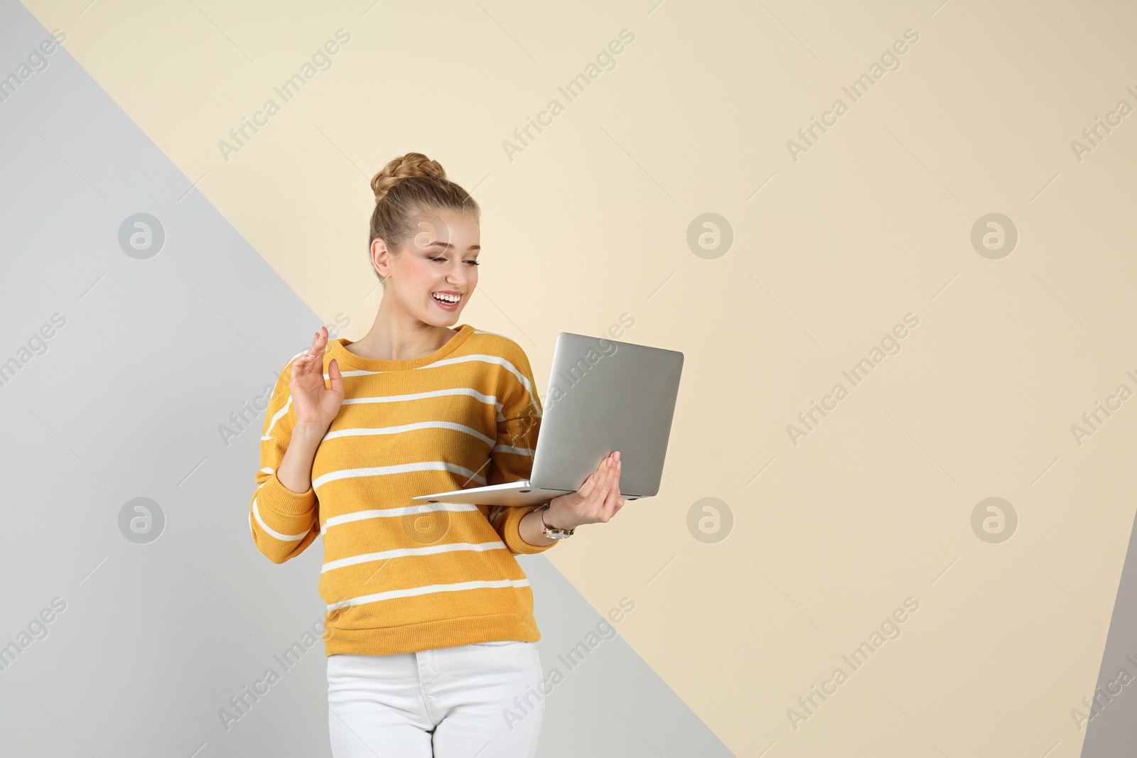 Photo of Young beautiful woman using laptop on color background. Space for text