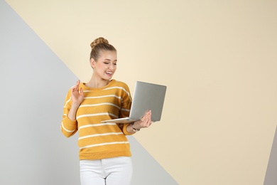 Photo of Young beautiful woman using laptop on color background. Space for text