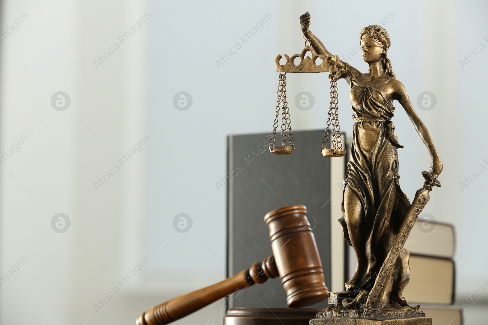 Photo of Figure of Lady Justice, gavel and books on white background, space for text. Symbol of fair treatment under law