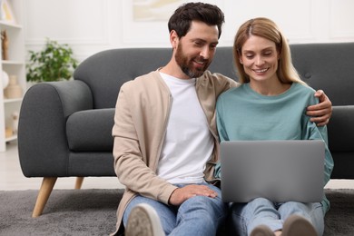Happy couple spending time together and using laptop at home