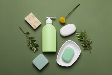 Photo of Soap bars and bottle dispenser on green background, flat lay