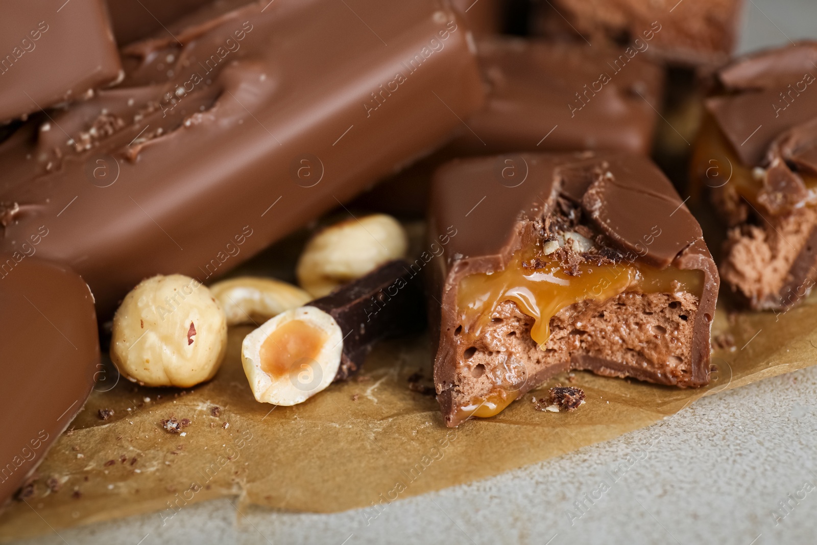 Photo of Delicious chocolate candy bars with nuts on light table, closeup