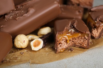 Delicious chocolate candy bars with nuts on light table, closeup