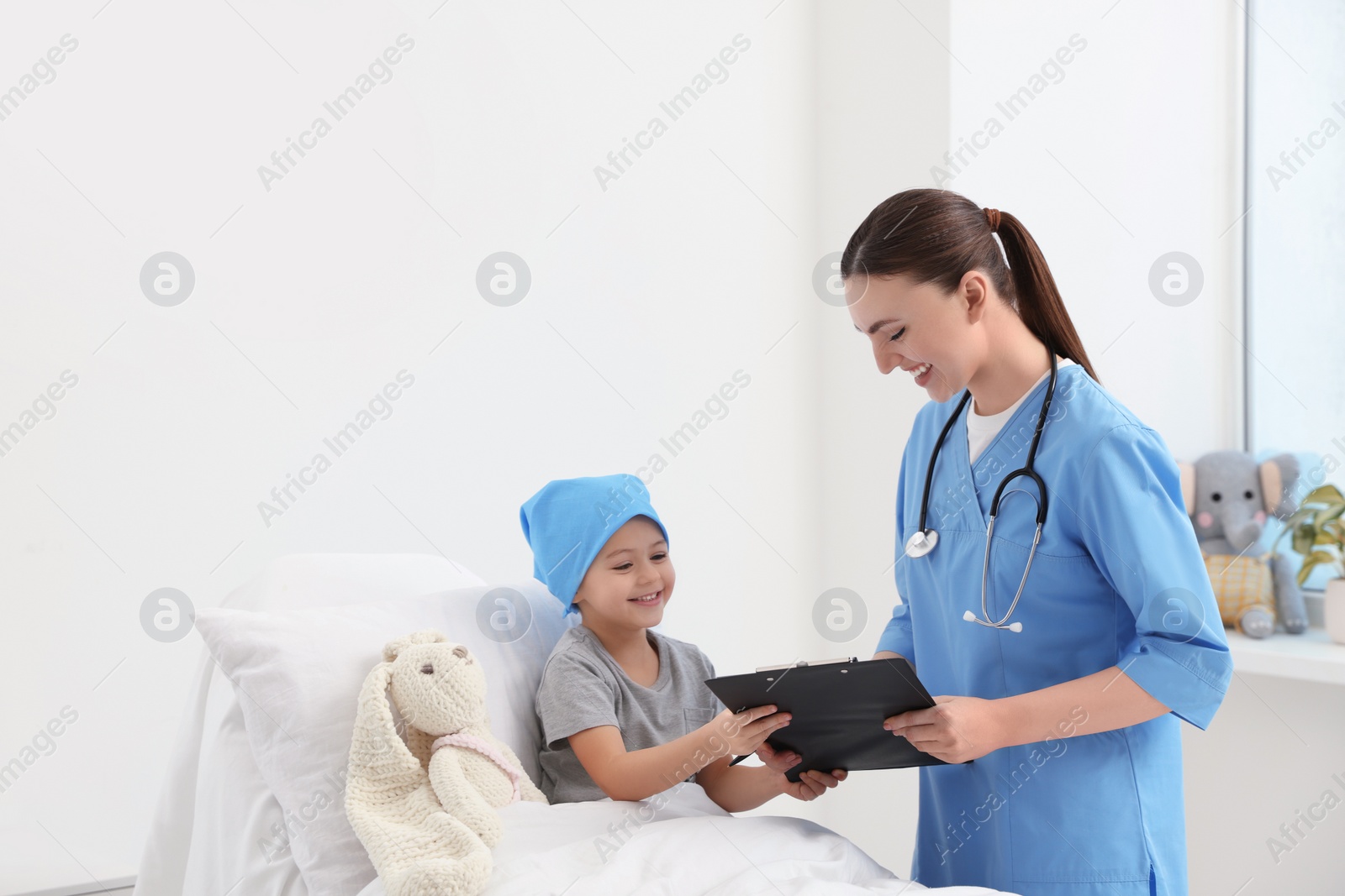 Photo of Childhood cancer. Doctor with clipboard and little patient in hospital