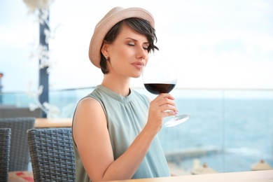 Young woman with glass of red wine at table outdoors