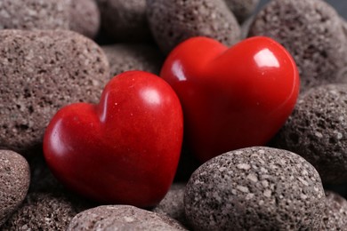 Photo of Red decorative hearts on stones, closeup view