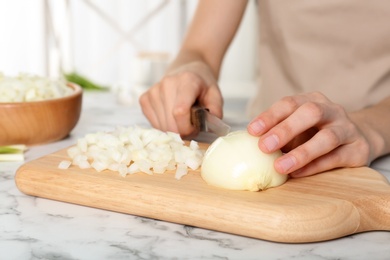 Photo of Woman cutting onion on wooden board, closeup