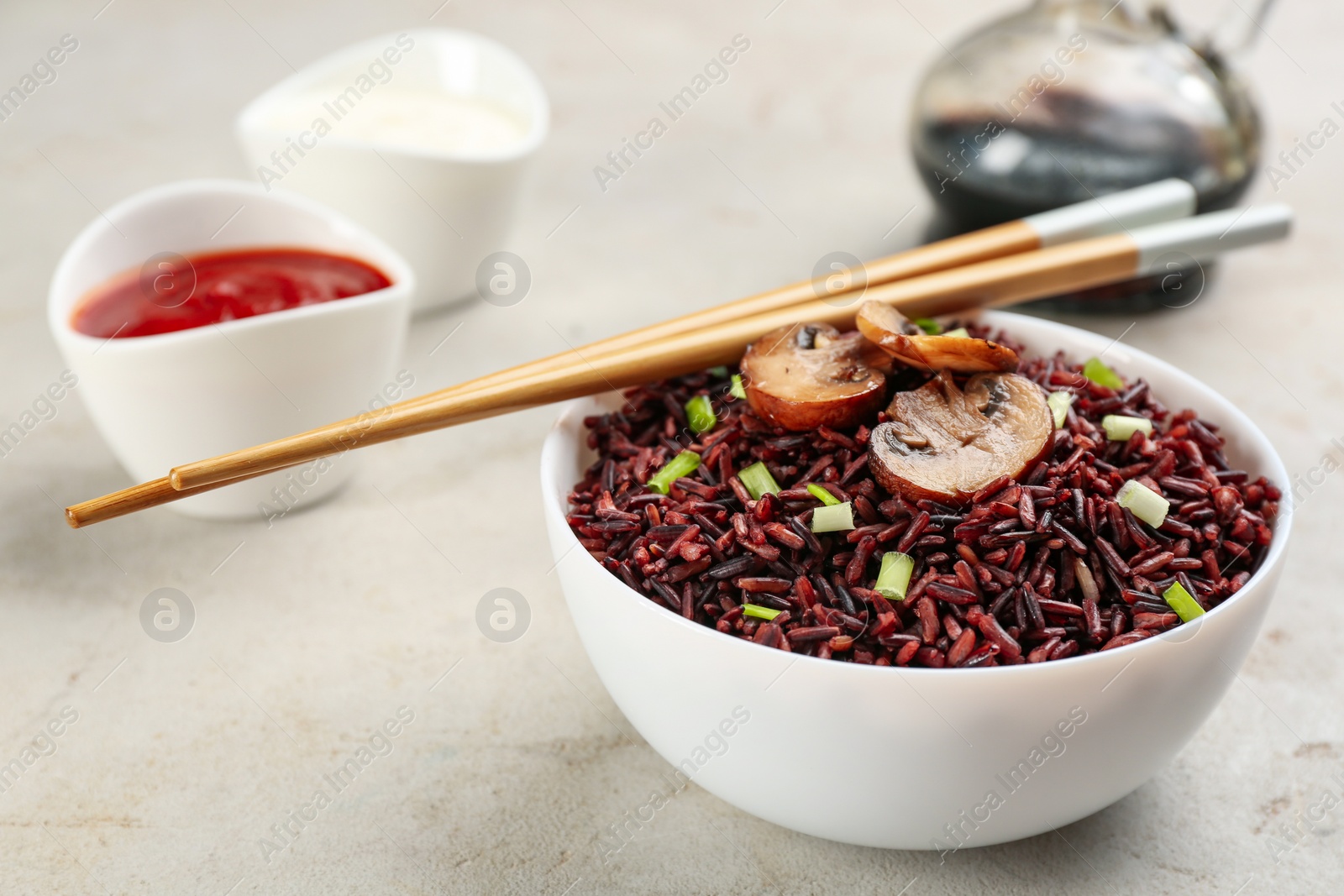 Photo of Tasty brown rice with mushrooms on light grey table