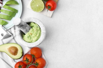 Mortar with delicious guacamole and ingredients on white table, flat lay. Space for text