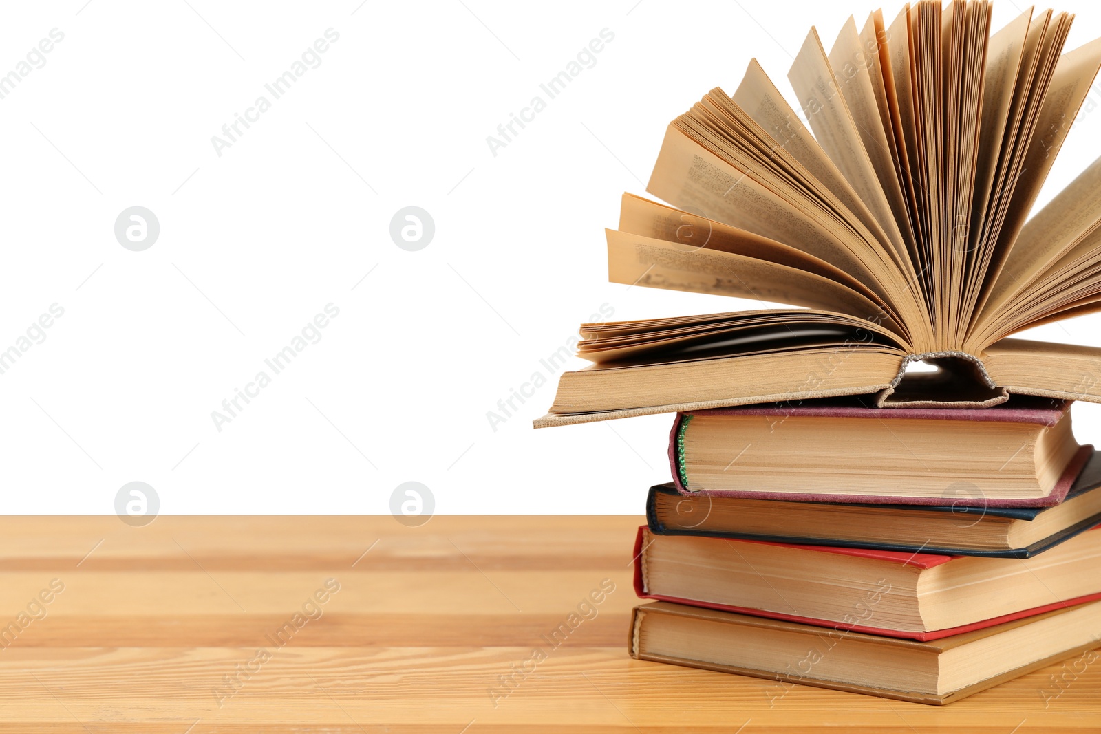 Photo of Stack of books on wooden table against white background. Library material