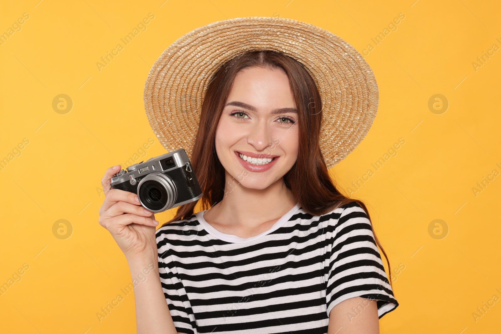 Photo of Young woman with camera on yellow background. Interesting hobby
