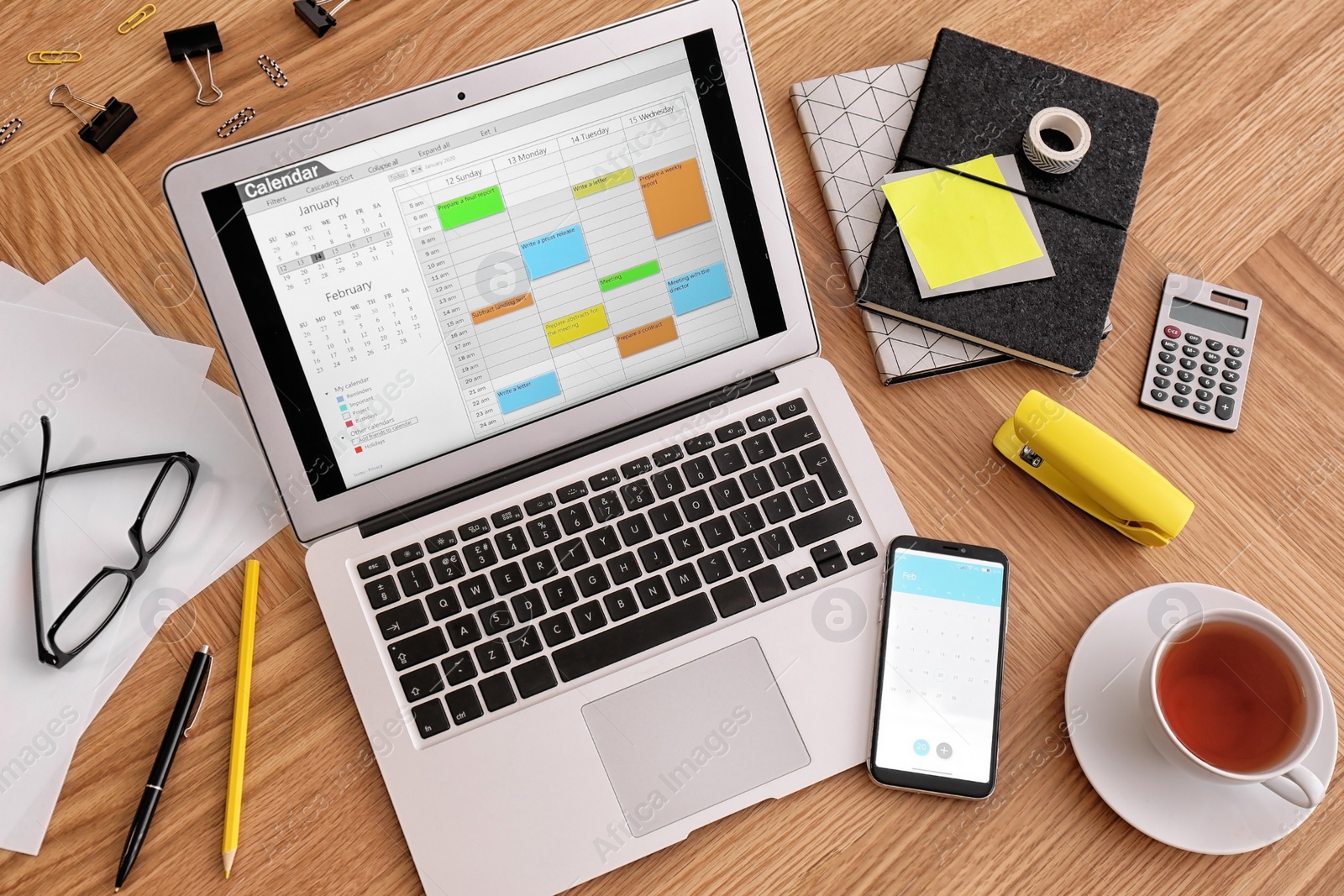 Photo of Modern laptop with calendar on wooden table, above view