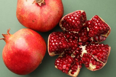 Photo of Fresh ripe pomegranates on pale green background, top view
