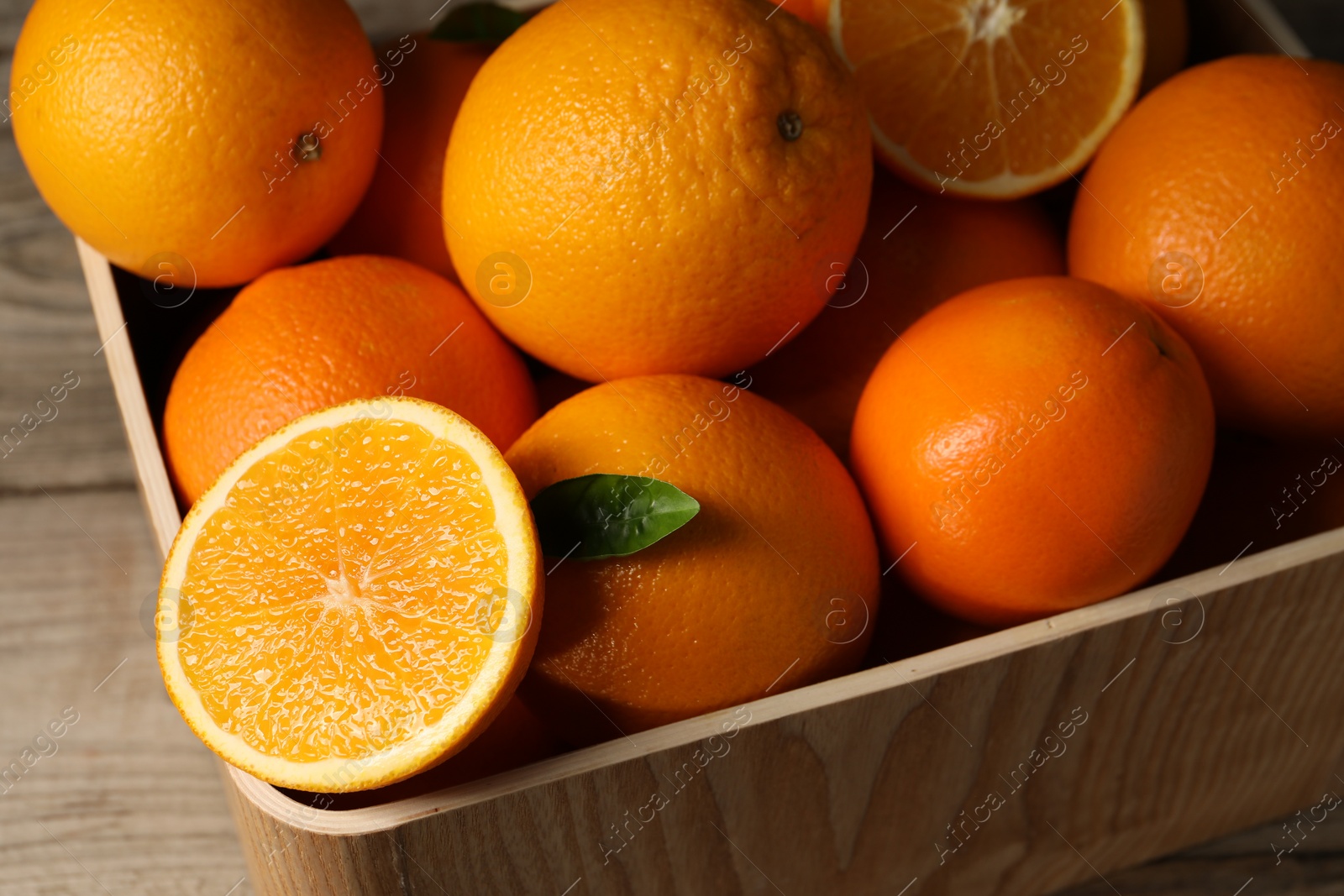Photo of Many whole and cut ripe oranges on wooden table, closeup