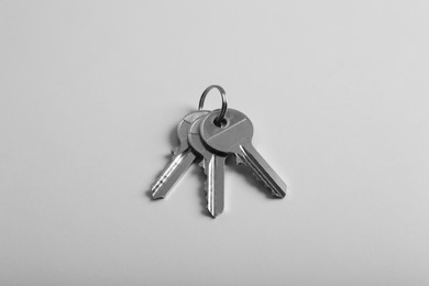 Keys on light grey background, above view. Real estate agent services