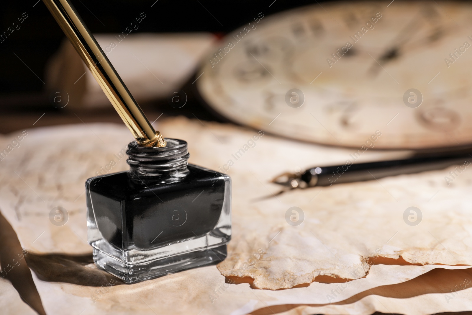 Photo of Inkwell with fountain pen on vintage parchment, closeup. Space for text