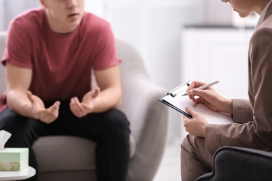 Psychotherapist working with young man in office, closeup