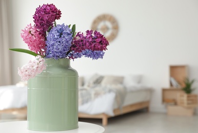 Photo of Beautiful hyacinths in metal can on table indoors, space for text. Spring flowers