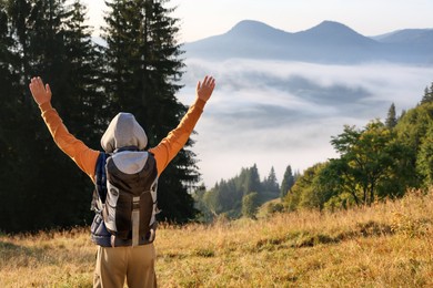 Photo of Tourist with backpack in mountains on sunny day, back view. Space for text