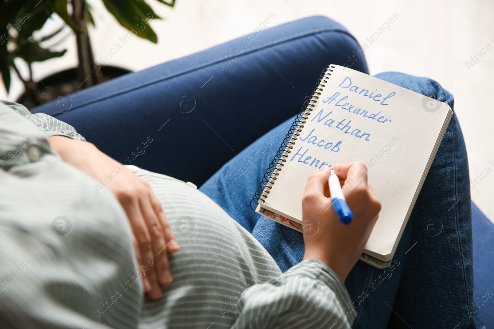 Photo of Pregnant woman with baby names list sitting in armchair, closeup