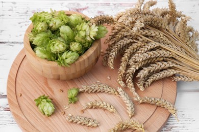 Photo of Fresh green hops and ears of wheat on white wooden table