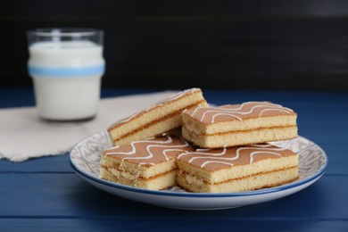 Tasty sponge cakes and milk on blue wooden table