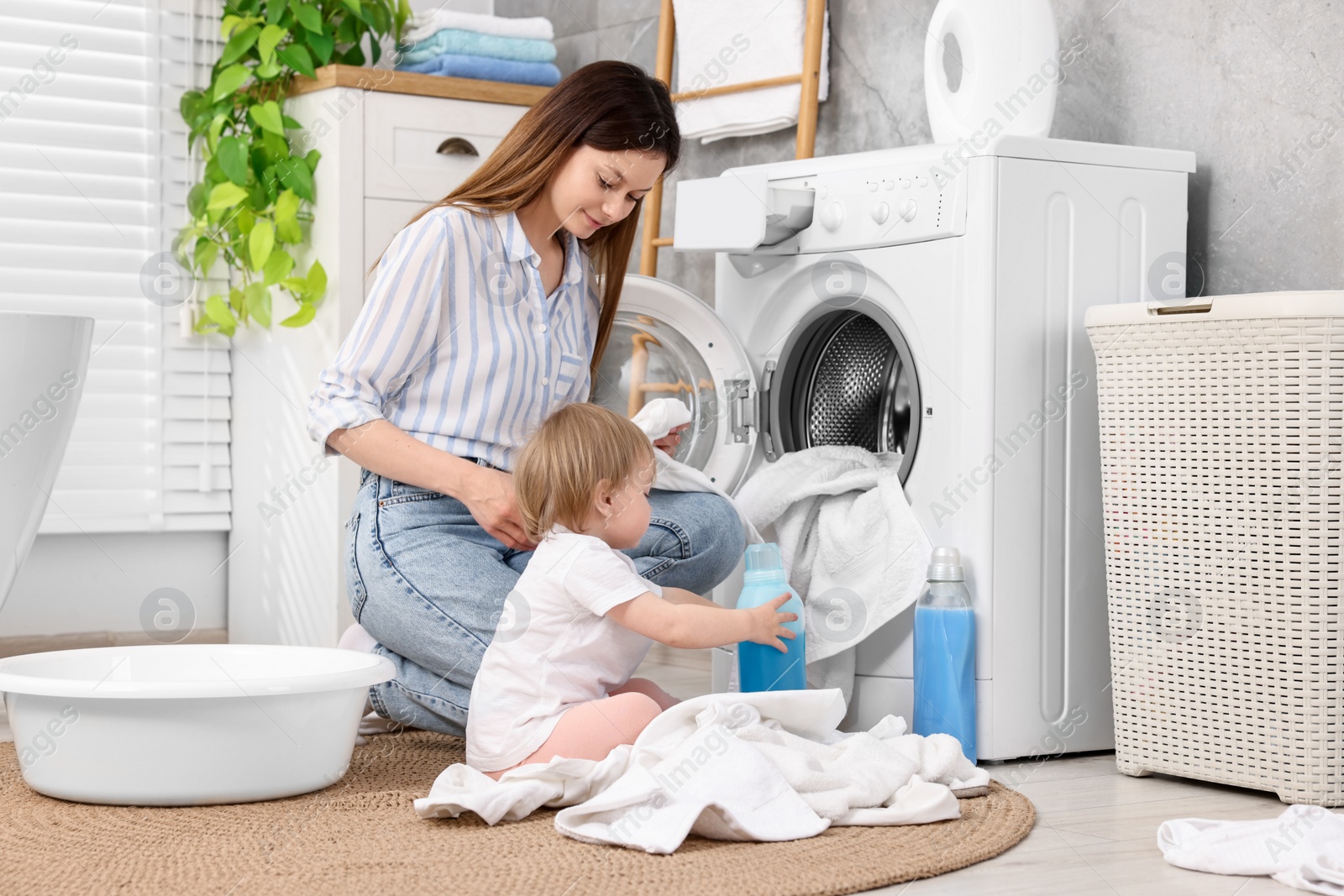 Photo of Mother with her daughter washing baby clothes in bathroom