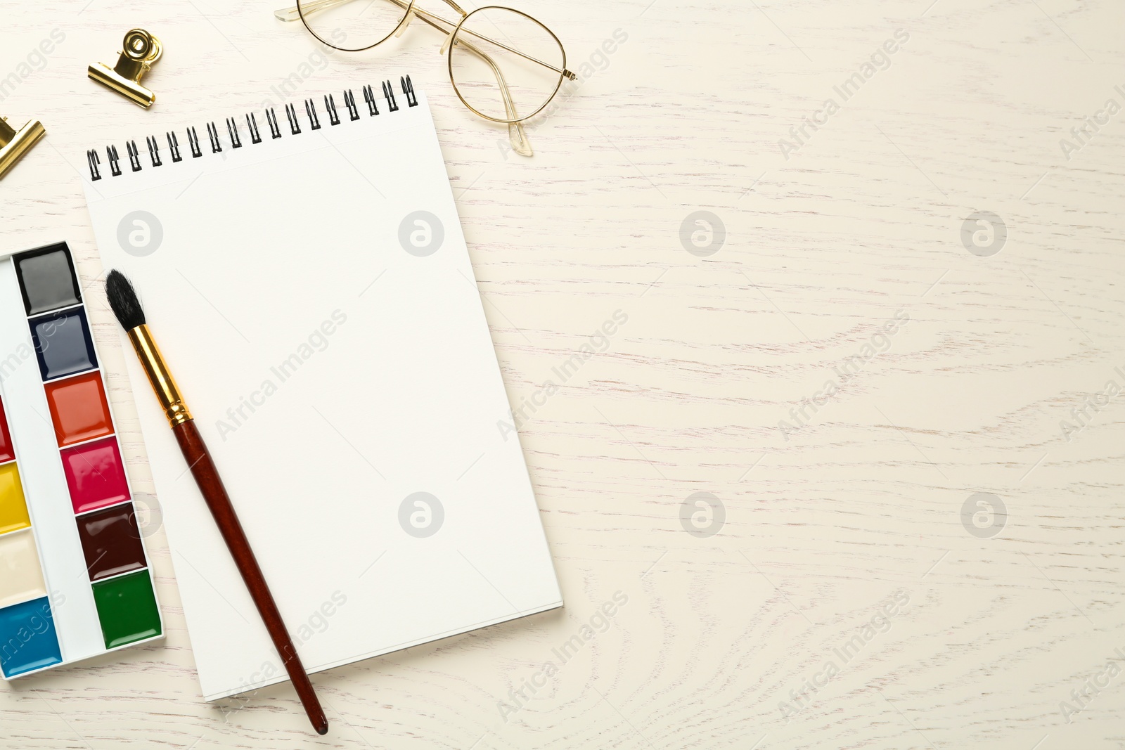 Photo of Flat lay composition with blank sketchbook on white wooden table. Space for text