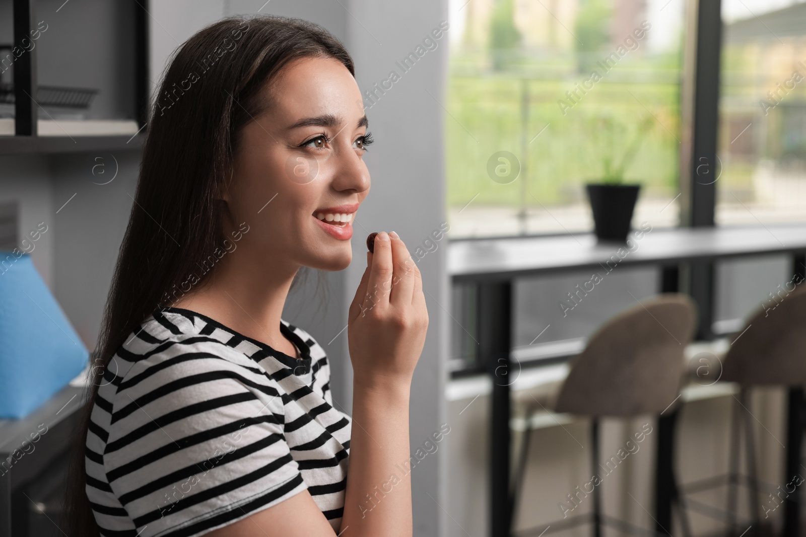 Photo of Young woman eating cherry in hostel kitchen