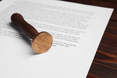 Photo of One stamp tool and document on wooden table, closeup