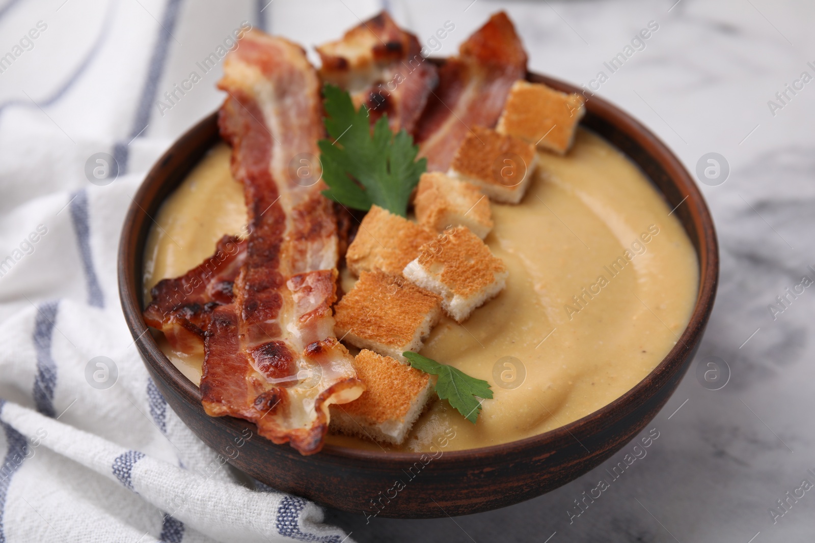 Photo of Delicious lentil soup with bacon and parsley in bowl on light marble table, closeup