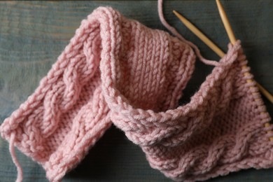 Photo of Pink knitting and needles on wooden table, flat lay