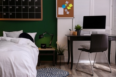 Modern teenager room interior with comfortable bed against green wall