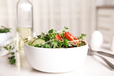 Photo of Salad with fresh organic microgreen in bowl on white table indoors