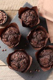 Photo of Delicious chocolate muffins on wooden table, top view