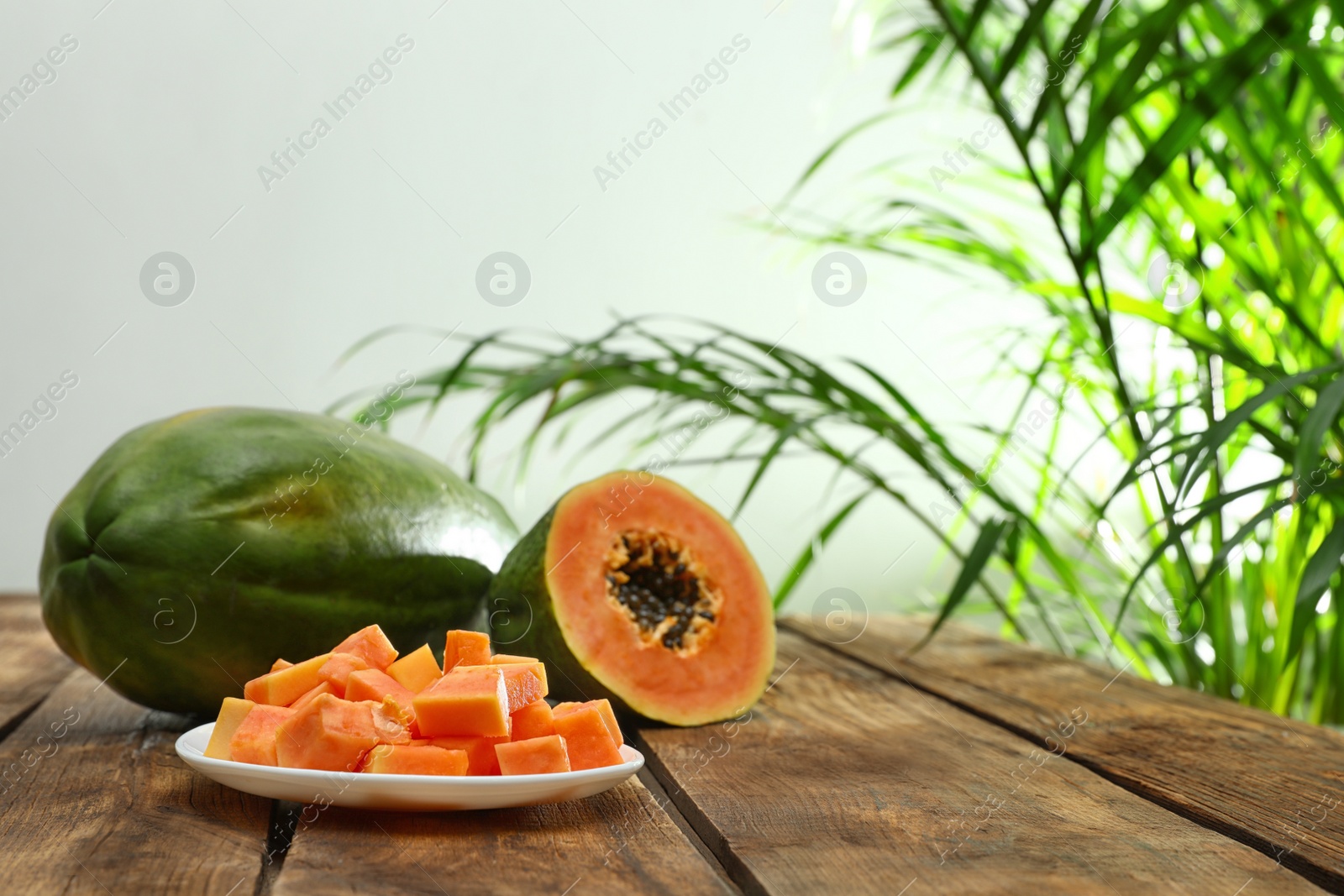 Photo of Fresh juicy papayas on wooden table against blurred background, space for text