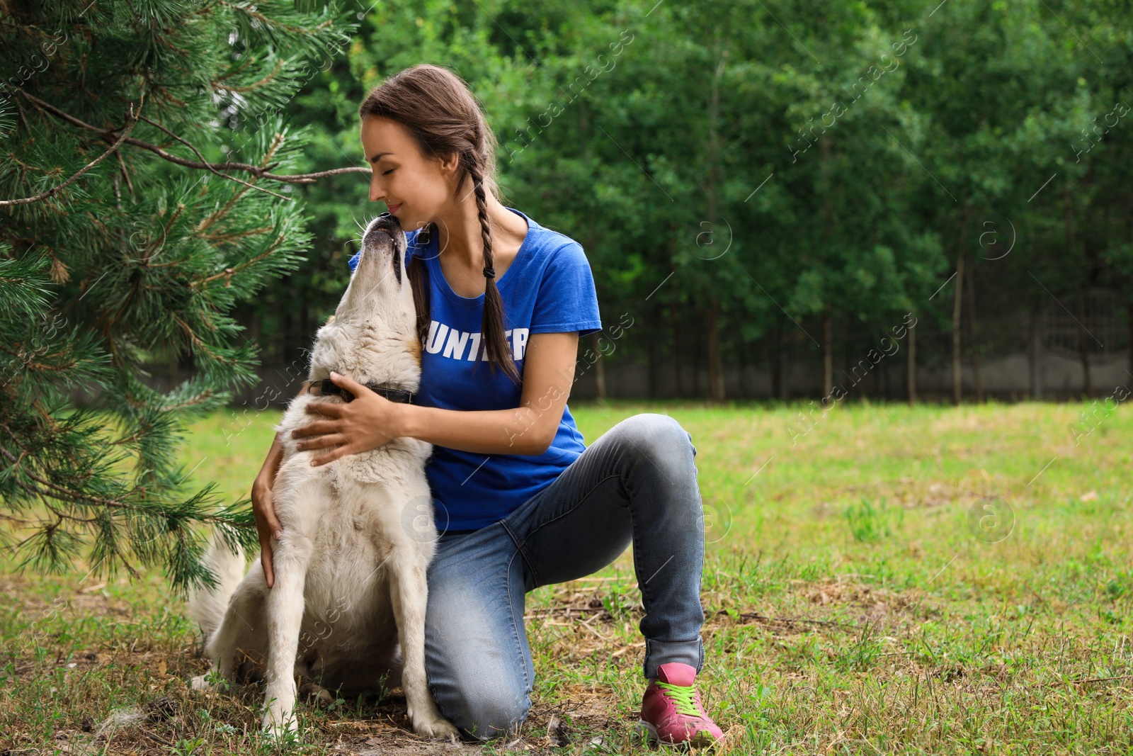 Photo of Female volunteer with homeless dog at animal shelter outdoors