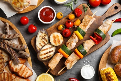 Flat lay composition with barbecued meat and vegetables on grey table