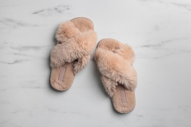Photo of Pair of soft slippers on white marble floor, top view