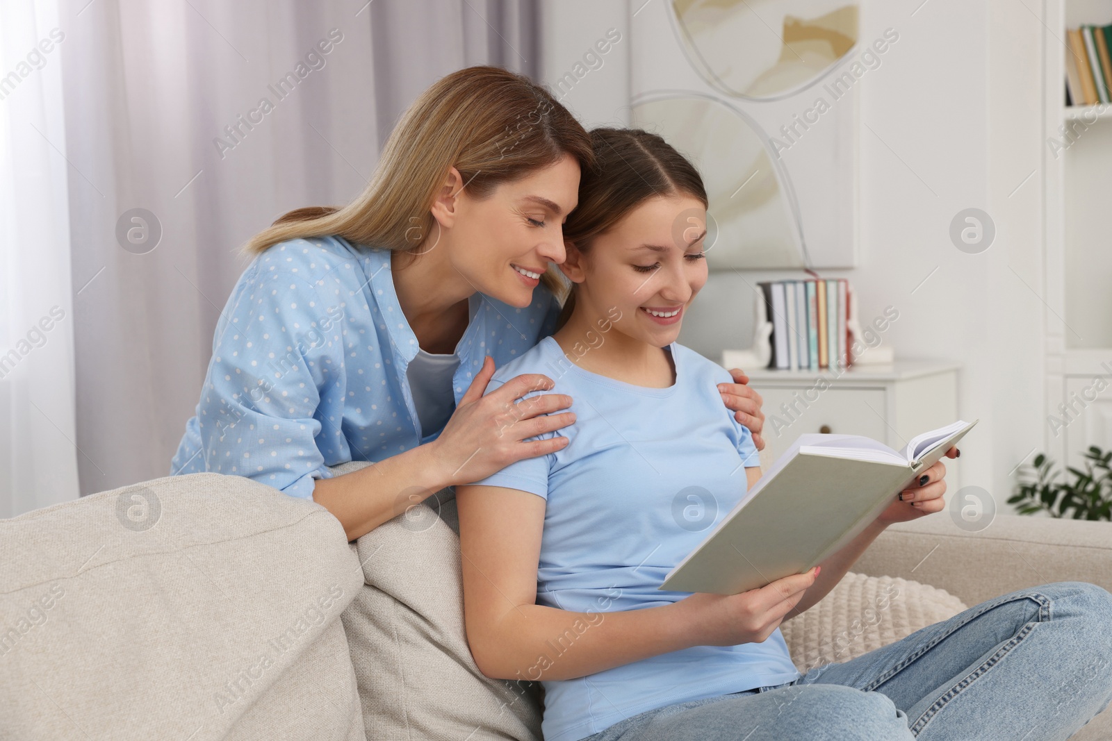 Photo of Happy mother and her teenage daughter spending time together with book at home