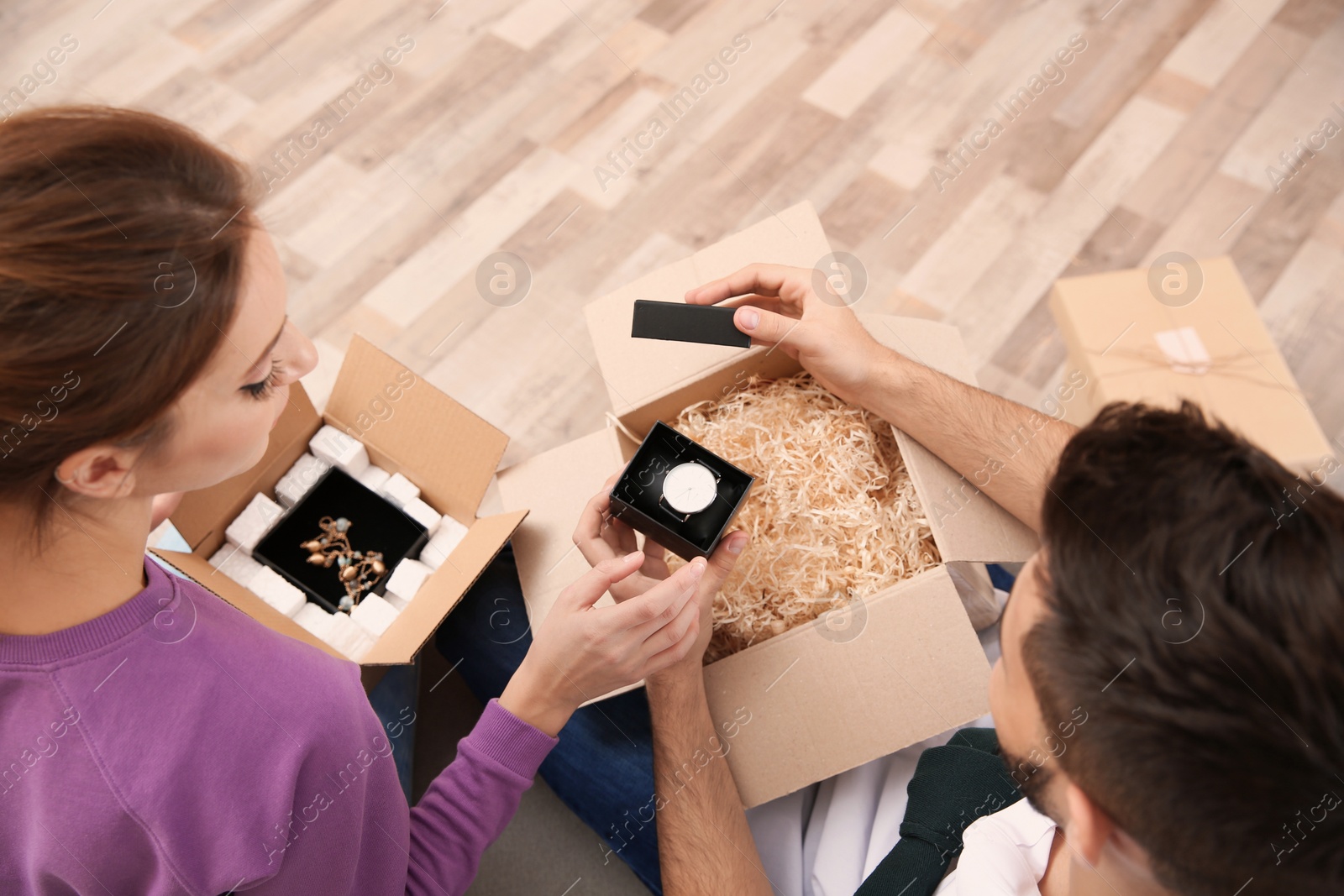 Photo of Young couple opening parcels at home, closeup