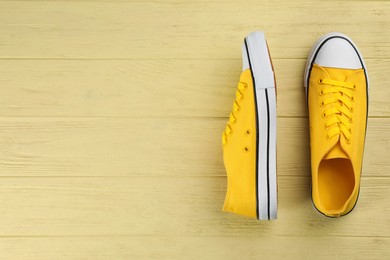Photo of Pair of stylish sneakers on yellow wooden table, flat lay. Space for text