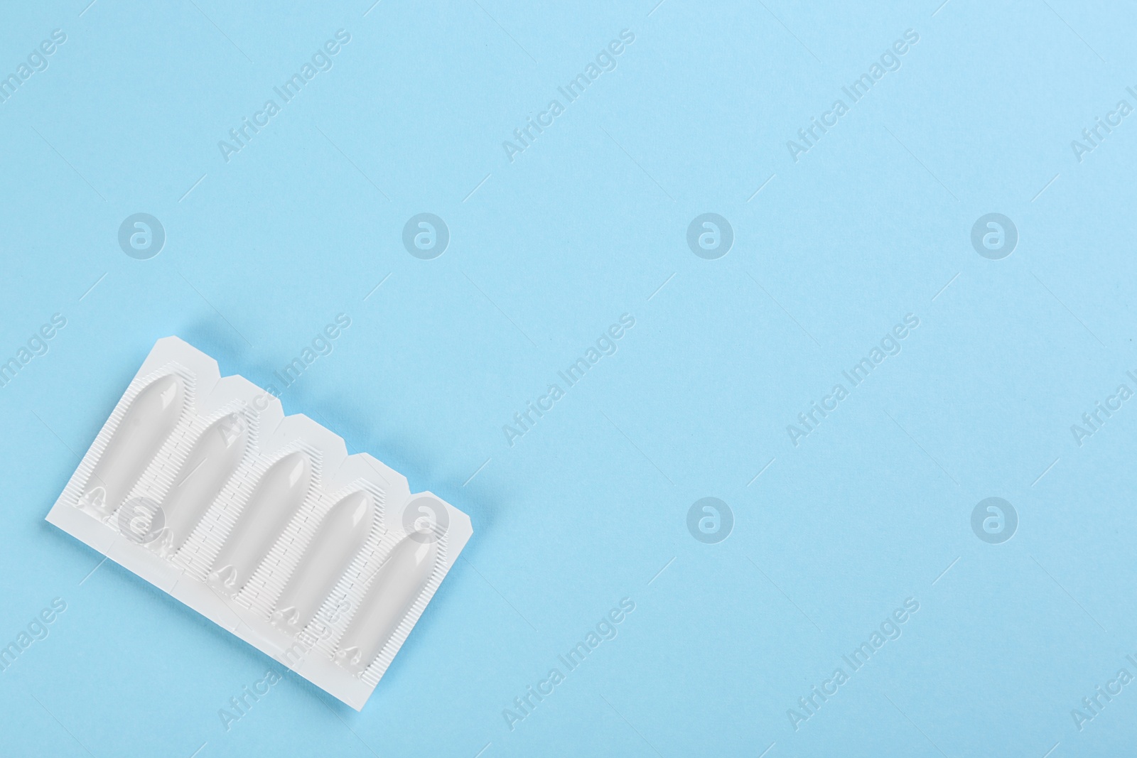 Photo of Suppositories and space for text on light blue background, top view. Hemorrhoid treatment