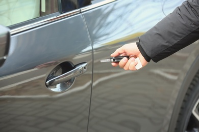 Photo of Closeup view of man opening car door with key