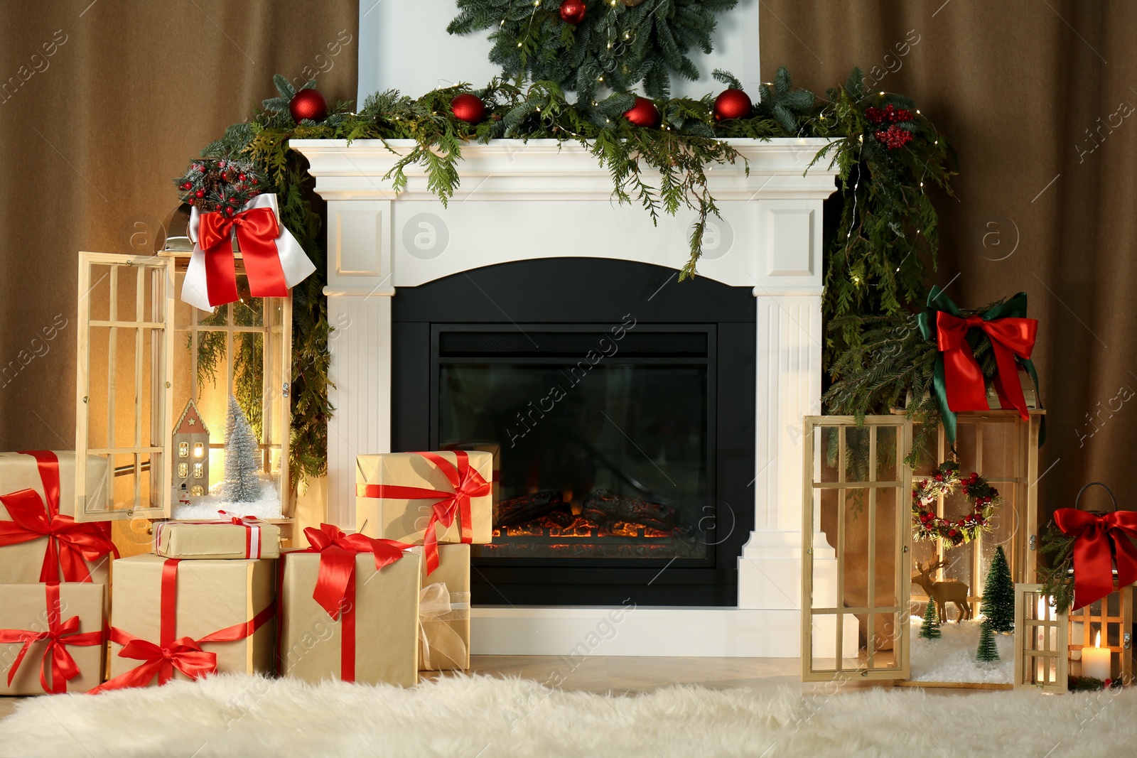 Photo of Beautiful Christmas lanterns and presents near fireplace in room with festive decor