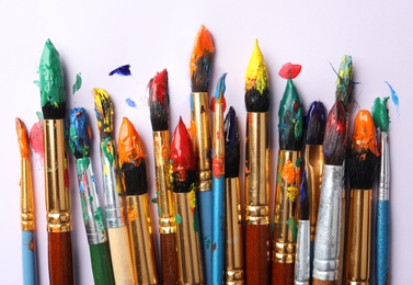 Photo of Brushes with colorful paints on white background, flat lay