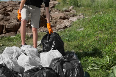 Photo of Man with trash bags full of garbage outdoors, closeup. Environmental Pollution concept