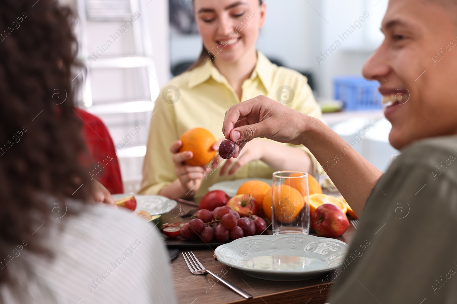 Photo of Friends eating vegetarian food at wooden table indoors