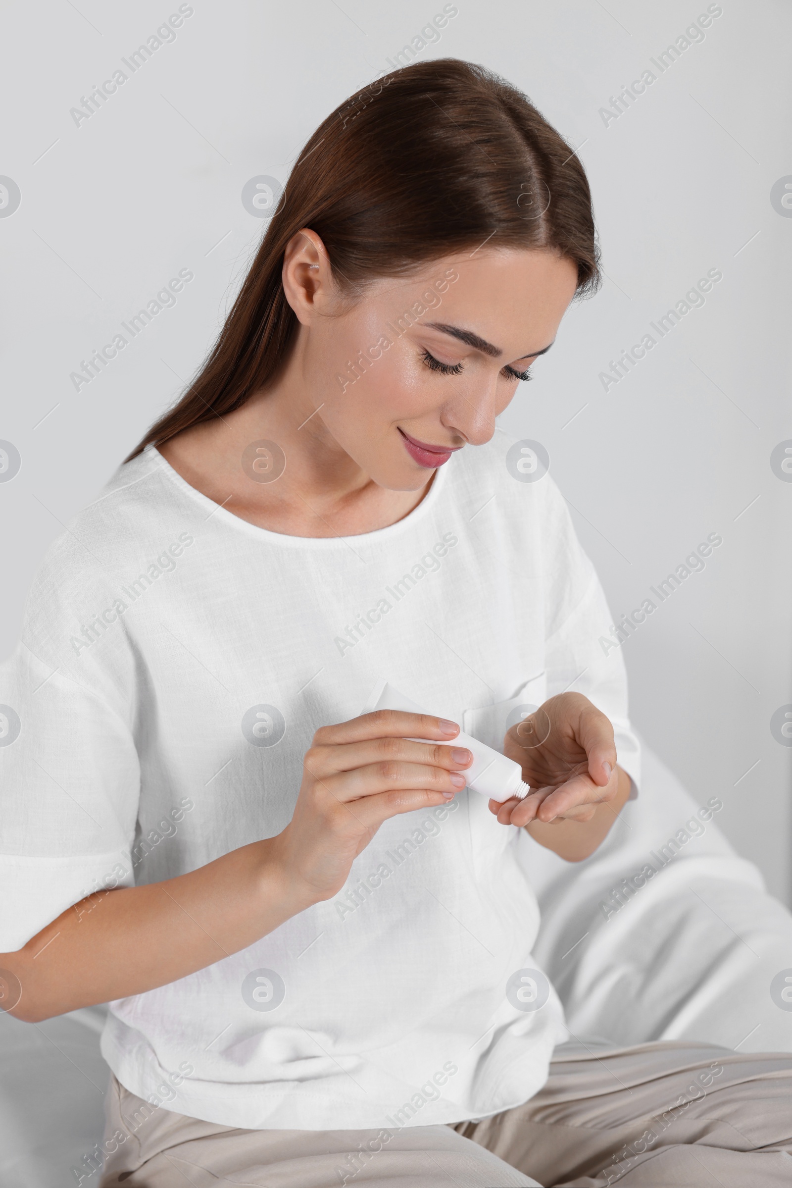 Photo of Woman applying cream on her hand indoors